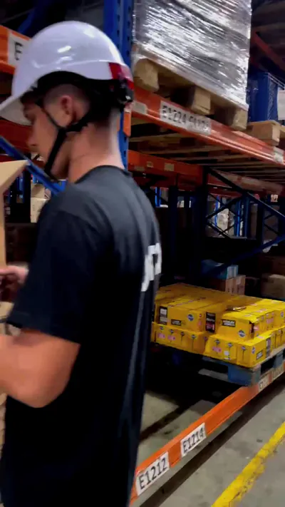 Auxiliar logístico verificando el inventario en una estantería de bodega